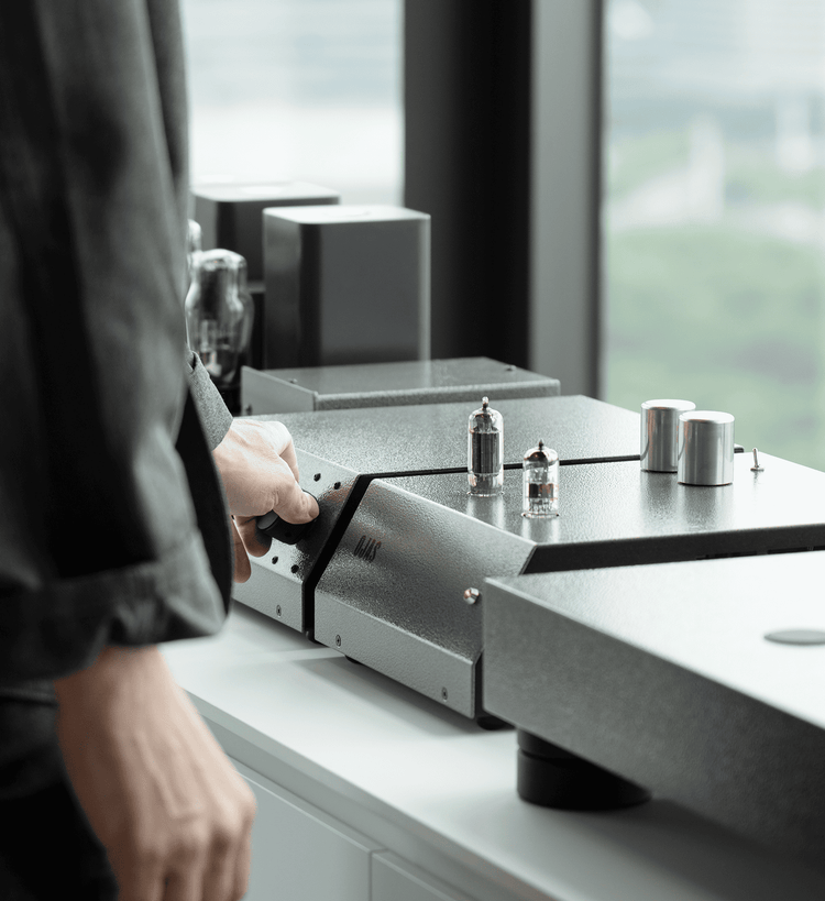 Hand adjusts knob on tube amplifier.