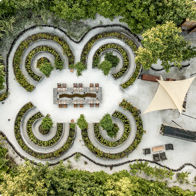 Aerial view of a long dining table in tropical courtyard.