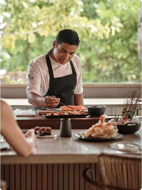 A chef prepares sushi at counter